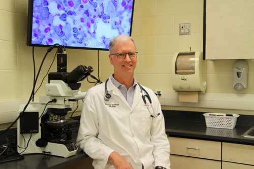 A man wearing a white lab coat standing inside a veterinary facility