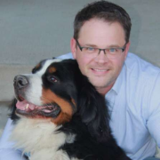 Photo depicts a man cuddling a dog.